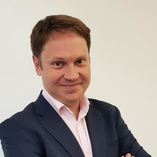 A white man with short brown hair and a shirt with suit jacket